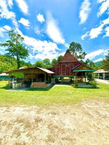 a large wooden building with a grass field in front at Kampung House (Minang) in Hulu Yam, Batang Kali in Batang Kali