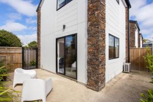 a home with a brick wall and white chairs at Charming Sunny Warm 10 Mins CBD Book Now in Christchurch
