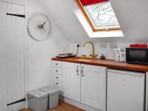 a kitchen with white cabinets and a bicycle on the wall at Old Chimneys Studio in Lewes