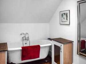 Old Chimneys Studio في لويس: حمام مع حوض استحمام مع منشفة حمراء