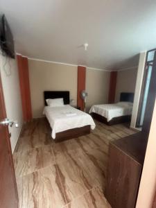 1 dormitorio con 2 camas en una habitación con suelo de madera en Cardos hostal, en Pisco