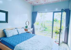 een blauwe slaapkamer met een bed en een glazen schuifdeur bij Homestay Nguyễn Hưng in Tân Tạo