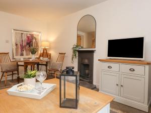 Una sala de estar con un televisor de pantalla plana sobre una cómoda. en The Wonky Burrow, en Bowness-on-Windermere