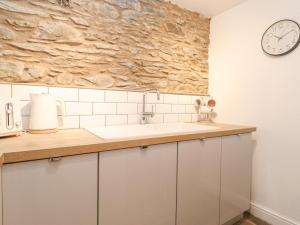 Una cocina con un fregadero y un reloj en la pared. en The Wonky Burrow, en Bowness-on-Windermere 15 fotos más