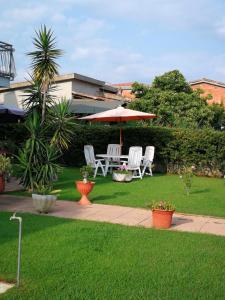 un patio con mesa, sillas y sombrilla en BB Guest House Ogliastra en Tortolì