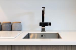 a kitchen sink with a faucet and two jars at Affordable Apartment Hagley Park Super Fast Wifi in Christchurch