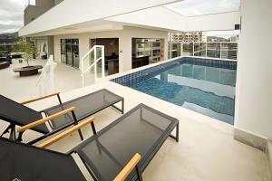 a swimming pool in a house with chairs and a table at Nosso Apê 915: Central | Academia | Piscina NA0714 in Juiz de Fora