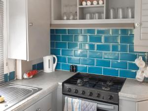 a kitchen with blue tile on the wall at Kingfisher - Uk41950 in Louth