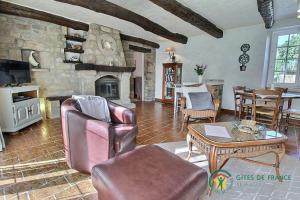 a living room with a couch and a stone fireplace at De la quenouille in Locoal-Mendon