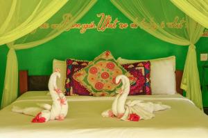 a bed with two swans made out of towels at Bali Bohemia Huts in Ubud