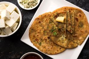 a white plate of food with a naan and cheese at Collection O 78675 Collection O Key Rooms in New Delhi