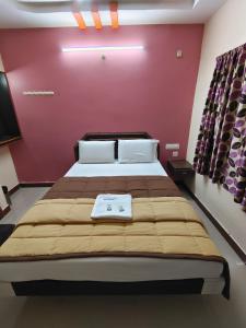 a bedroom with a large bed with a red wall at Hotel DKR Residency in Tirupati