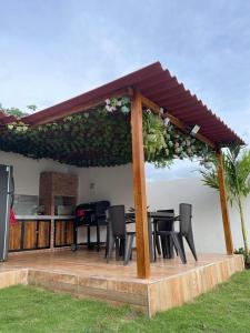 eine Terrasse mit einem Tisch und Stühlen unter einem Pavillon in der Unterkunft CASA CAMPESTRE A POCOS MINUTOS DE CARTAGENA in Santa Rosa