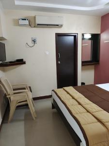 a bedroom with a bed and a chair in it at Hotel DKR Residency in Tirupati