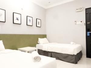 duas camas num quarto com branco e verde em # Hashtag Hotel - Self Check in em Alor Setar