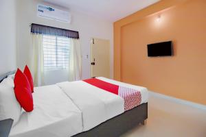 a bedroom with a bed with red pillows and a television at OYO Flagship 77067 P N K Suites in Jālahalli