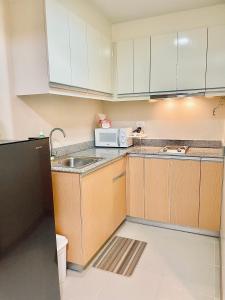 a kitchen with a sink and a microwave at Eli's sunset crib - The Palladium in Iloilo City