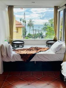 Cama en habitación con ventana grande en PorterHouse Beach Hotel, en Patong Beach
