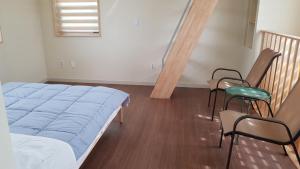 ein Schlafzimmer mit einem Bett, zwei Stühlen und einer Treppe in der Unterkunft Sopoong in Jeju-do