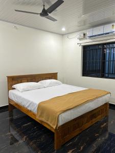 - une chambre avec un lit en bois et un ventilateur de plafond dans l'établissement Yashovana Nature Stay Gokarna, à Gokarna