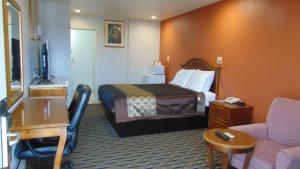 CorcoranにあるCorcoran Country Innのベッドとデスクが備わるホテルルームです。