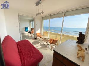 Sala de estar con sofá rojo y vistas al océano en Appartement Valras-Plage, 4 pièces, 6 personnes - FR-1-781-14, en Valras-Plage