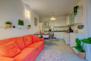 sala de estar con sofá naranja y cocina en Lenni Apart Swimming Pool and lake - Happy Rentals, en Leggiuno