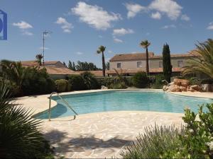 een groot zwembad in een tuin met palmbomen bij Maison Valras-Plage, 2 pièces, 6 personnes - FR-1-781-18 in Valras-Plage