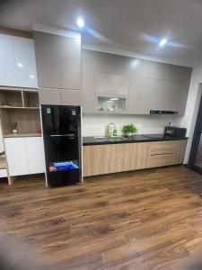 a kitchen with a black refrigerator and white cabinets at Mami House - Luxcity Cẩm Phả Serviced Apartments in Cẩm Phả