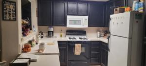 a kitchen with black cabinets and a white refrigerator at Be our Guest - Shared Home Lancaster in Palmdale