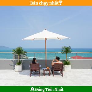 un homme et une femme assis sous un parasol sur la plage dans l'établissement SOCO Hotel by THG, à Đà Nẵng