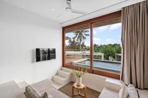 a living room with a large window and a pool at Pagi Villas by Hombali in Mengwi