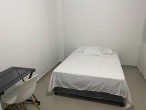 Habitación blanca pequeña con cama y escritorio en HOTEL IBIZA, en Valledupar
