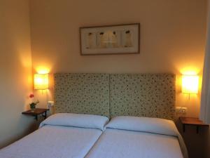 a bedroom with two beds and two lights on the wall at 5 bedrooms house with wifi at Molinaseca in Molinaseca