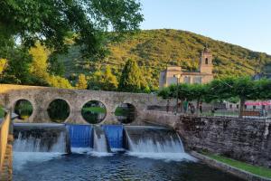 a stone bridge over a river with two waterfalls at 5 bedrooms house with wifi at Molinaseca in Molinaseca
