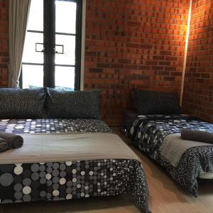 two beds in a room with a brick wall at AZJA@BROGA in Mantin
