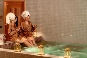 two women are sitting in a swimming pool at Awaken Da Nang Hotel in Danang