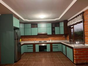 eine Küche mit grünen Schränken und einem Kühlschrank in der Unterkunft Estancia Esperanza Quinta Vacacional 
