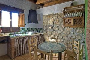 een keuken met een tafel en een stenen muur bij 6 bedrooms house with shared pool jacuzzi and wifi at Montefrio in Montefrío