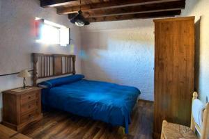 een slaapkamer met een blauw bed en een houten dressoir bij 6 bedrooms house with shared pool jacuzzi and wifi at Montefrio in Montefrío