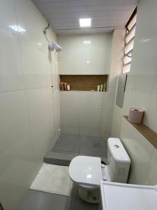 La salle de bains blanche est pourvue d'une douche et de toilettes. dans l'établissement Casa próximo ao Maracanã, à Rio de Janeiro