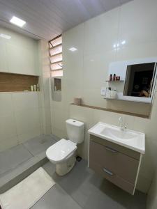 La salle de bains blanche est pourvue de toilettes et d'un lavabo. dans l'établissement Casa próximo ao Maracanã, à Rio de Janeiro