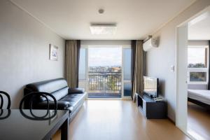 a living room with a couch and a bed and a television at Kensington Resort Jeju Hanlim in Jeju