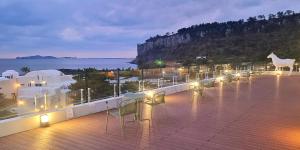 a balcony with tables and chairs and a view of the ocean at Lareem Boutique Hotel in Seogwipo