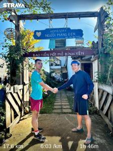 two men shaking hands in front of a gate at Người Măng Đen Homestay in Kon Von Kla