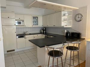 eine Küche mit weißen Schränken und einer schwarzen Arbeitsplatte in der Unterkunft Ferienwohnung Sellin in Ostseebad Sellin + 13 Fotos