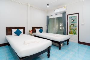 two beds in a room with white walls and blue floors at The Palm Krabi Residence And Resort in Ban Khlong Chi Lat