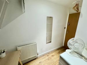 a room with a white wall and a fan at Kamilla's Rooms London Zone-1 in London