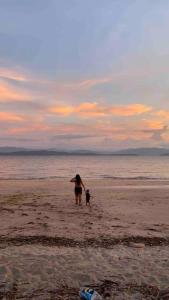 Eine Frau und ein Kind, die am Strand spazieren in der Unterkunft Hospedaje el viejo y el mar in El Pájaro