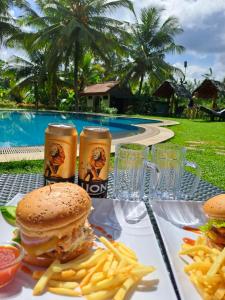 a table with a hamburger and french fries and drinks at The Nature Park Villa in Sigiriya